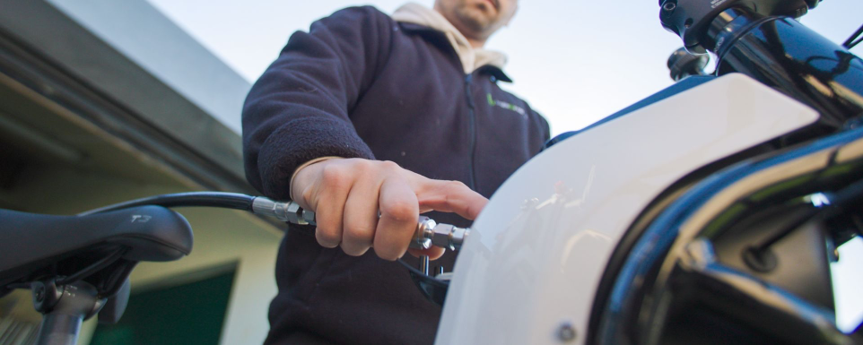 Technicien raccordant un système d’alimentation hydrogène sur vélo électrique